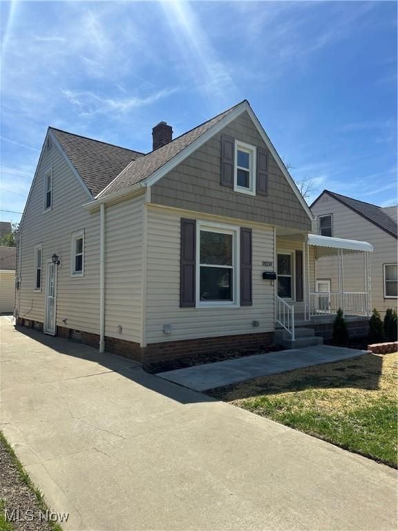 bungalow-style home featuring roof with shingles, covered porch, and a chimney