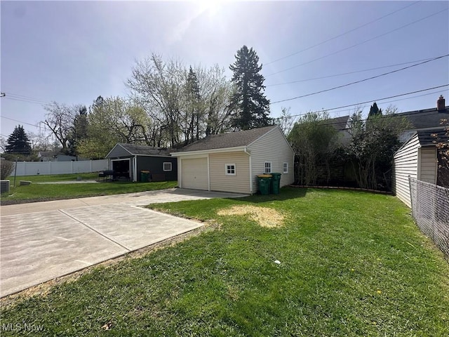 view of yard featuring fence, an outdoor structure, concrete driveway, and a detached garage