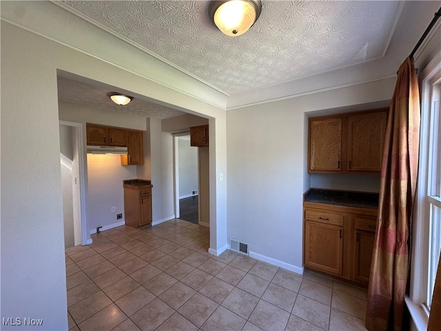 kitchen featuring visible vents, light tile patterned floors, dark countertops, and a textured ceiling