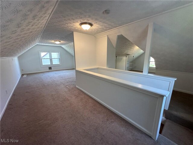 bonus room featuring baseboards, a textured ceiling, lofted ceiling, and carpet flooring