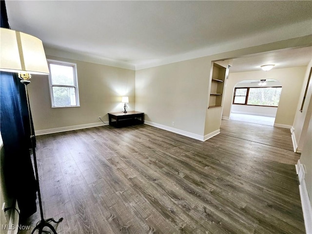 1893 Ridge Rd, Hinckley, OH 44233 - unfurnished living room with dark wood-style floors, baseboards, arched walkways, and a healthy amount of sunlight