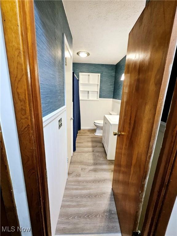 1893 Ridge Rd, Hinckley, OH 44233 - bathroom with a textured ceiling, toilet, wood finished floors, vanity, and wainscoting