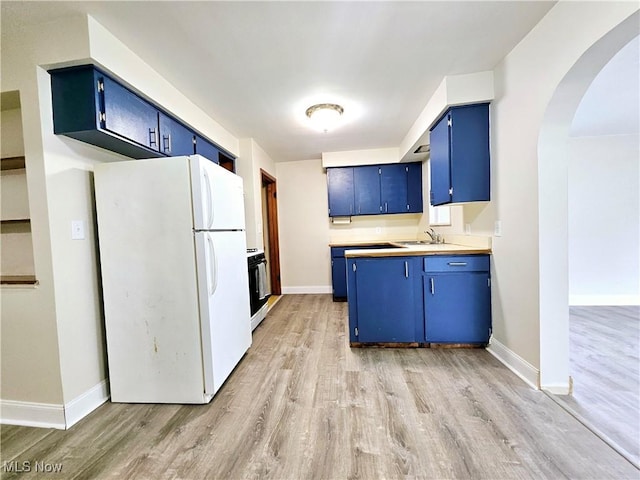 1893 Ridge Rd, Hinckley, OH 44233 - kitchen with light wood-type flooring, blue cabinets, freestanding refrigerator, and arched walkways