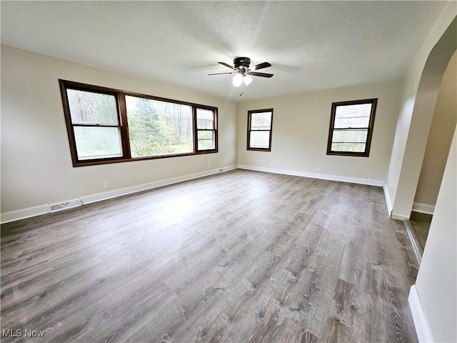 1893 Ridge Rd, Hinckley, OH 44233 - spare room featuring visible vents, ceiling fan, baseboards, arched walkways, and dark wood-type flooring