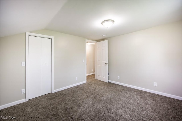 unfurnished bedroom with baseboards, a closet, carpet, and vaulted ceiling