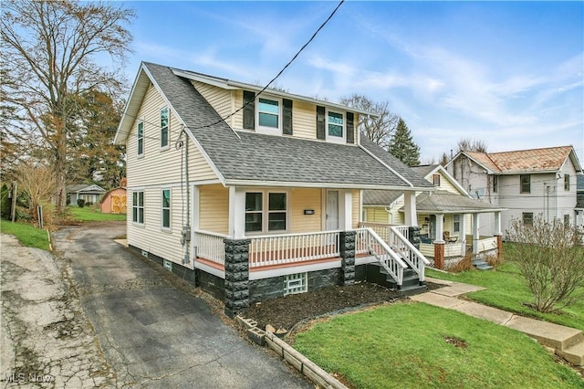 bungalow-style house featuring aphalt driveway, a front yard, covered porch, and roof with shingles