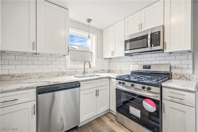 kitchen with white cabinets, stainless steel appliances, light wood-type flooring, and a sink