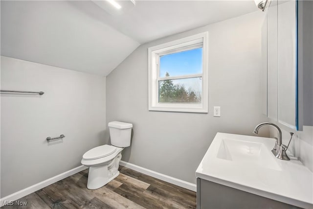 bathroom with wood finished floors, toilet, vanity, baseboards, and lofted ceiling
