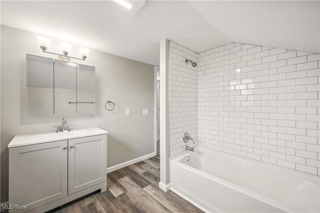 full bath with wood finished floors, vaulted ceiling, shower / washtub combination, vanity, and baseboards