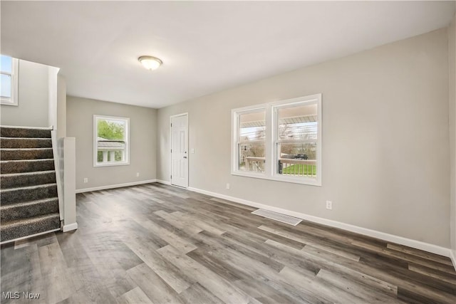 unfurnished living room with baseboards, stairway, visible vents, and dark wood-type flooring