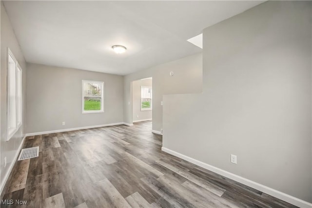 spare room featuring baseboards, visible vents, and dark wood-type flooring