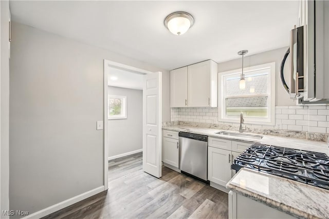 kitchen featuring white cabinetry, stainless steel appliances, decorative backsplash, and a sink