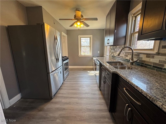 kitchen with a sink, ceiling fan, tasteful backsplash, baseboards, and appliances with stainless steel finishes