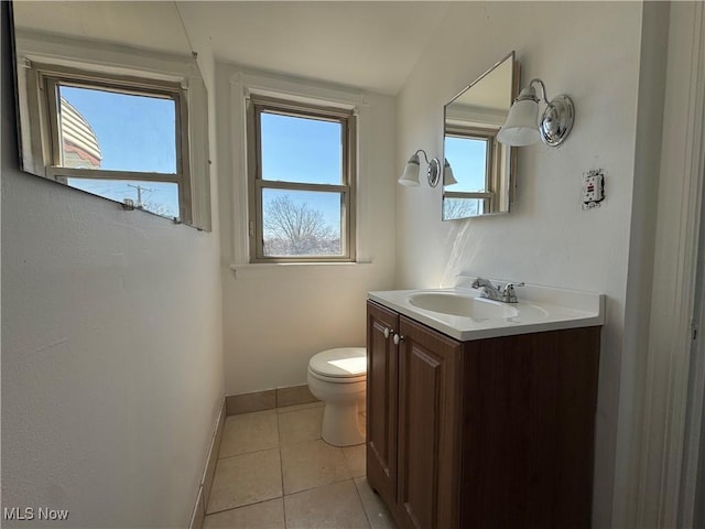 half bath featuring tile patterned floors, toilet, vanity, and baseboards