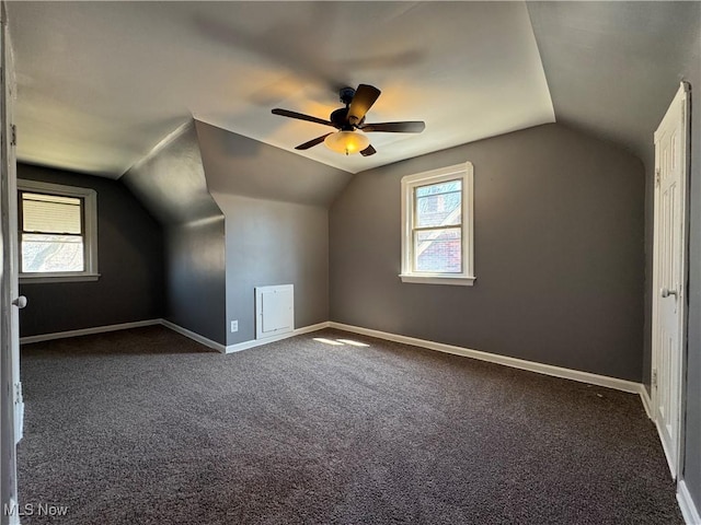 additional living space with ceiling fan, dark carpet, lofted ceiling, and baseboards