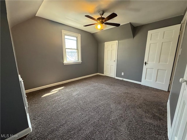 unfurnished bedroom featuring baseboards, dark colored carpet, ceiling fan, and lofted ceiling