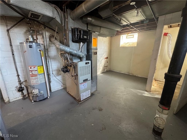 basement featuring water heater, visible vents, concrete block wall, and heating unit