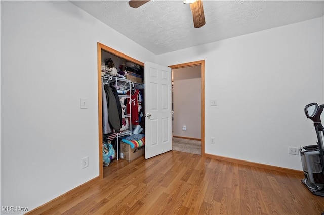 unfurnished bedroom with baseboards, a textured ceiling, a closet, and light wood-style flooring