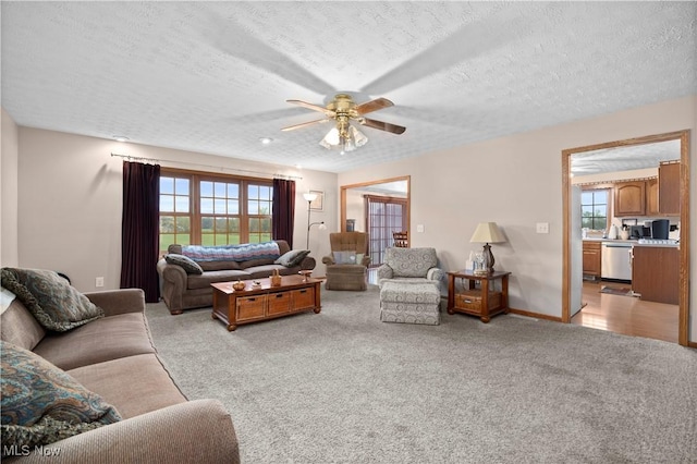 living room with a textured ceiling, a wealth of natural light, a ceiling fan, and light carpet