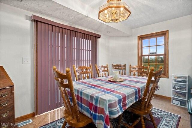 dining room with visible vents, an inviting chandelier, wood finished floors, and baseboards