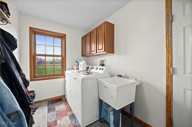 washroom with a sink, washing machine and clothes dryer, cabinet space, and baseboards