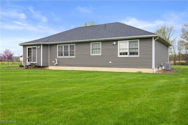 rear view of house featuring a lawn, a shingled roof, central air condition unit, and entry steps
