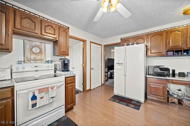 kitchen featuring white appliances, light wood-style floors, ceiling fan, and brown cabinets