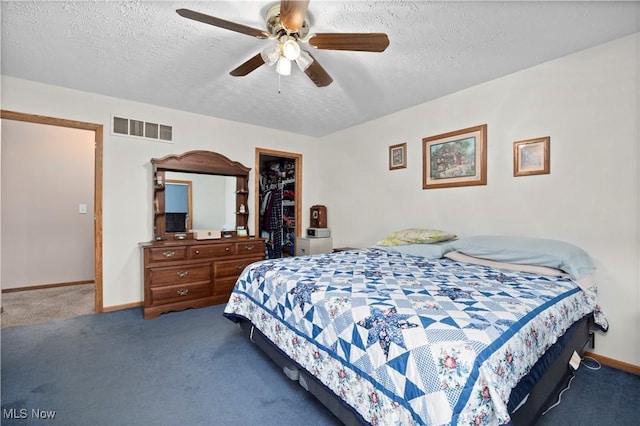 bedroom featuring carpet flooring, visible vents, baseboards, a textured ceiling, and a spacious closet