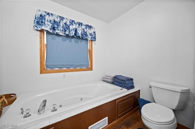 full bath featuring toilet, a jetted tub, visible vents, and wood finished floors