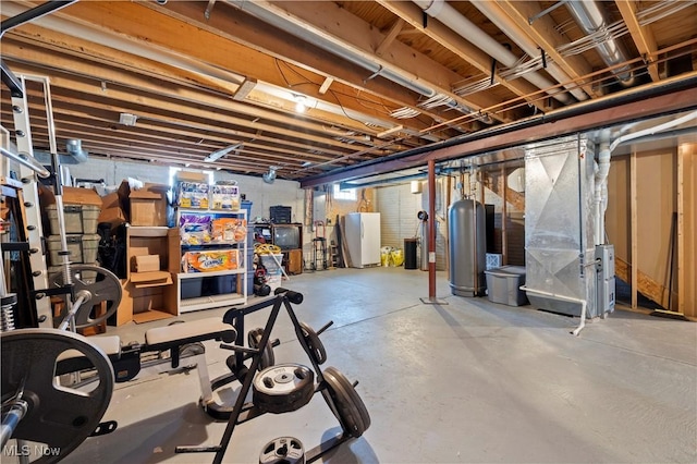 below grade area with heating unit, gas water heater, and fridge