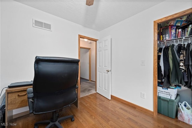 office space featuring baseboards, visible vents, and wood finished floors