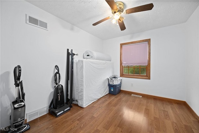 miscellaneous room featuring a ceiling fan, visible vents, and wood finished floors