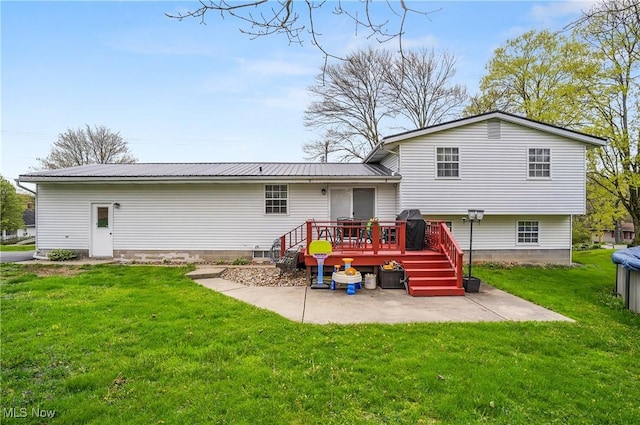 rear view of house featuring metal roof, a patio, a wooden deck, and a yard