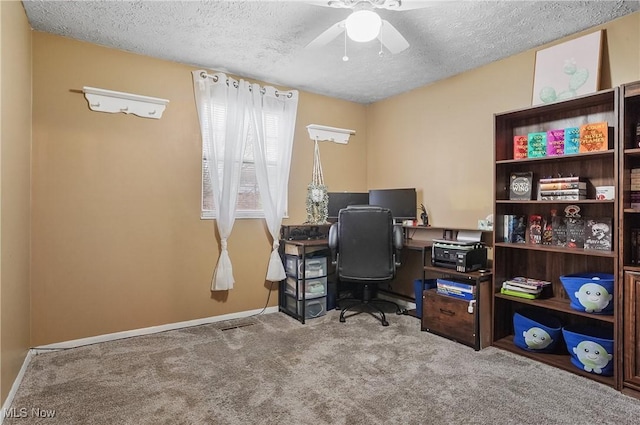carpeted home office featuring a textured ceiling, a ceiling fan, and baseboards