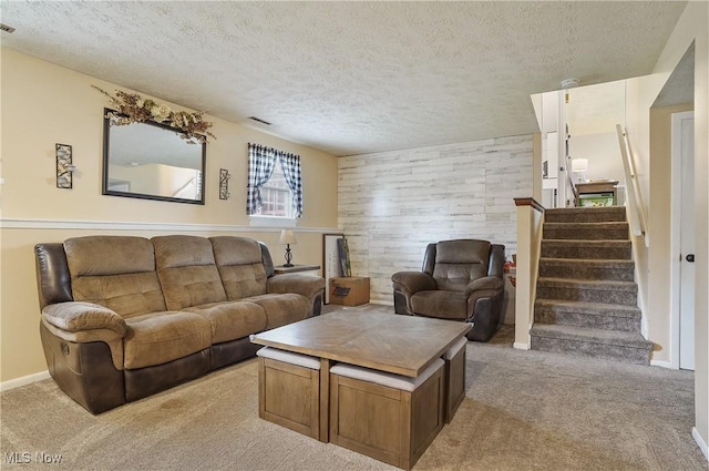 living room with wood walls, stairs, a textured ceiling, and carpet