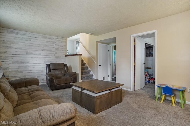 living room with a textured ceiling, stairs, light colored carpet, and baseboards
