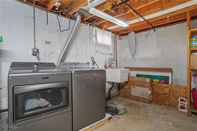 washroom with independent washer and dryer, concrete block wall, laundry area, and a sink