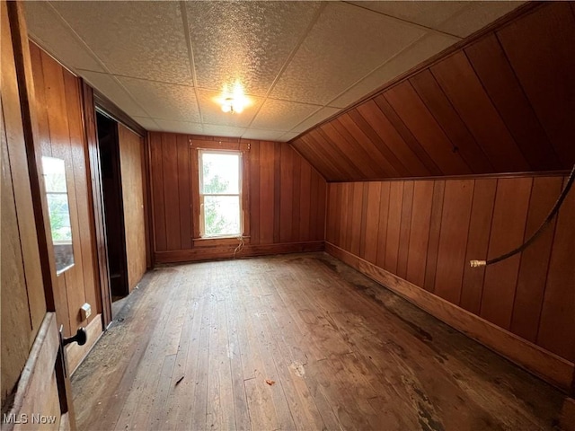 additional living space featuring wooden walls, vaulted ceiling, and light wood-style flooring