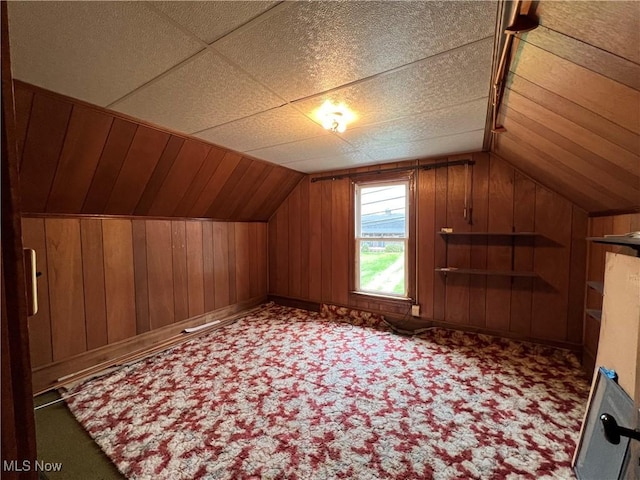 bonus room with carpet flooring, wood walls, and lofted ceiling