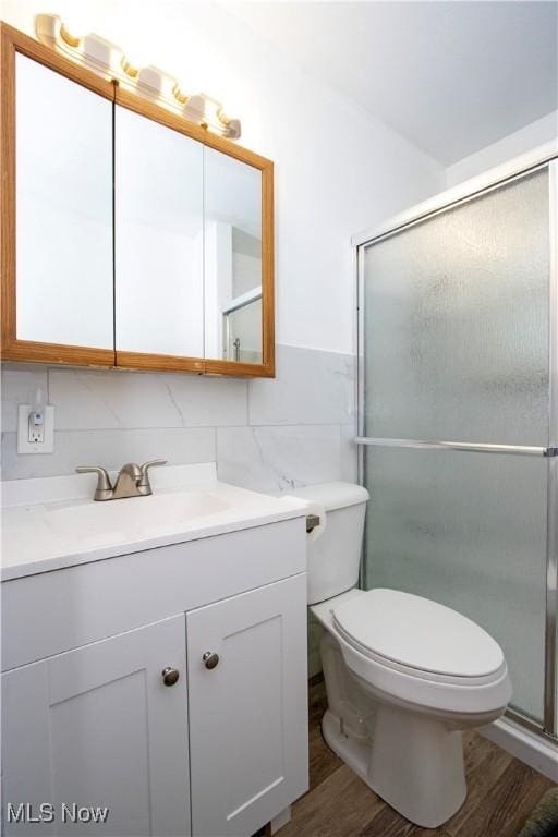 full bathroom featuring a stall shower, toilet, tile walls, wood finished floors, and vanity