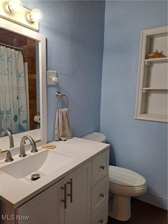 49197 John Tomcho Rd, Cumberland, OH 43732 - full bathroom featuring toilet, a textured wall, vanity, and curtained shower