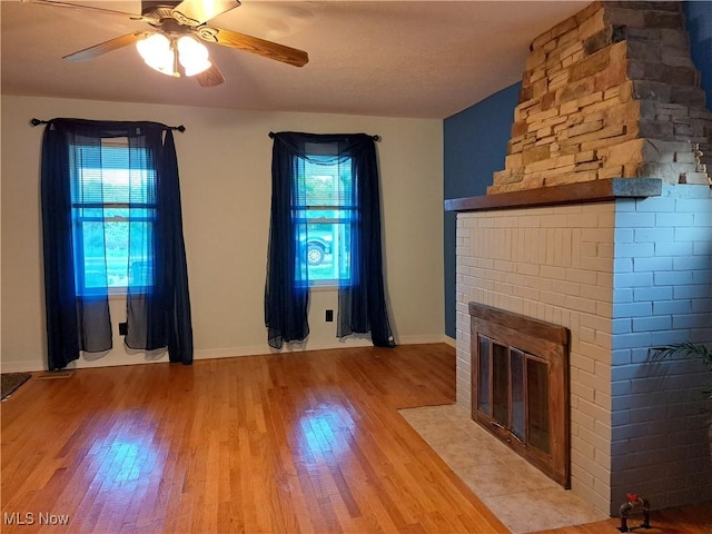 49197 John Tomcho Rd, Cumberland, OH 43732 - unfurnished living room with healthy amount of natural light, light wood-type flooring, a fireplace, and a ceiling fan