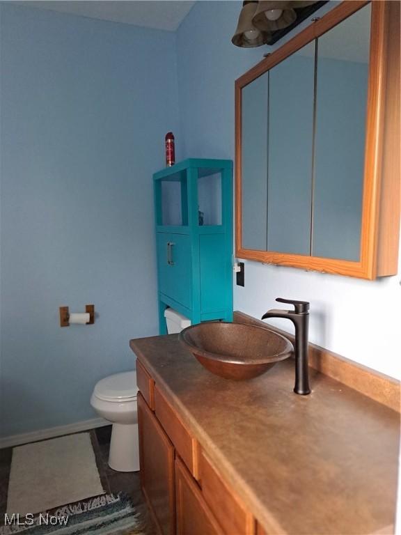 49197 John Tomcho Rd, Cumberland, OH 43732 - half bathroom featuring toilet, vanity, and baseboards