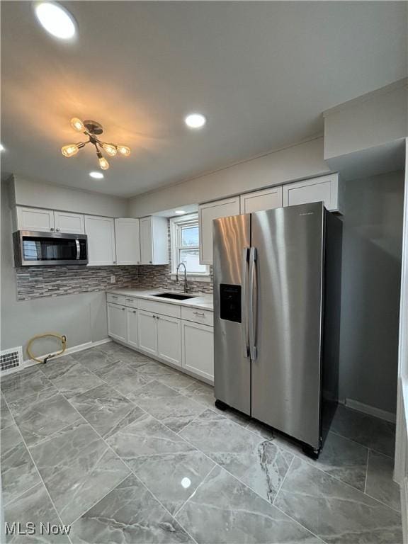 4399 W 57th St, Cleveland, OH 44144 - kitchen featuring white cabinets, appliances with stainless steel finishes, a sink, backsplash, and visible vents
