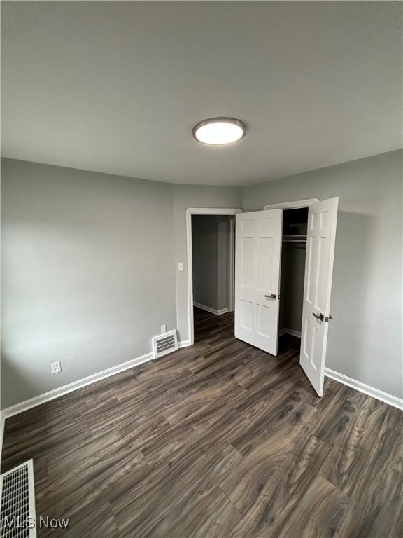 4399 W 57th St, Cleveland, OH 44144 - unfurnished bedroom featuring baseboards, a closet, dark wood-style floors, and visible vents