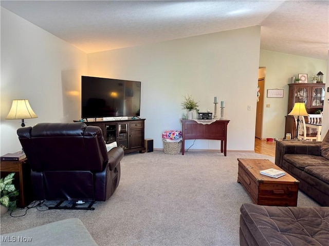living room featuring baseboards, vaulted ceiling, and light carpet
