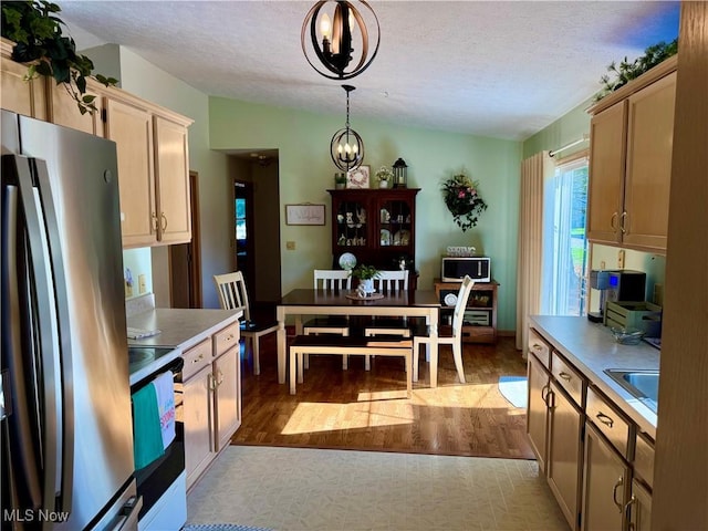 kitchen featuring dark wood finished floors, hanging light fixtures, appliances with stainless steel finishes, a textured ceiling, and lofted ceiling