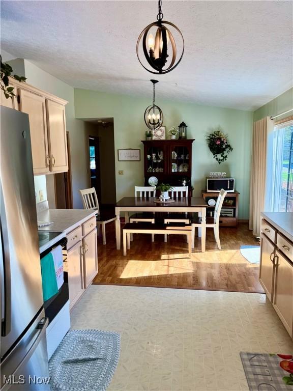dining space featuring a chandelier, baseboards, a textured ceiling, and light wood-style flooring