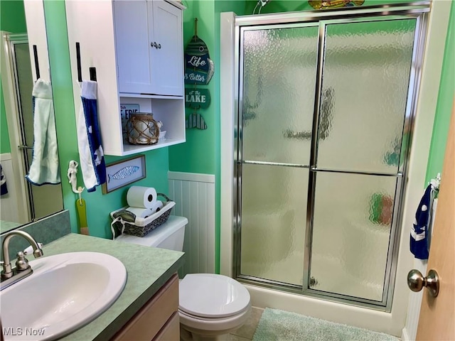full bath with toilet, vanity, and a shower stall
