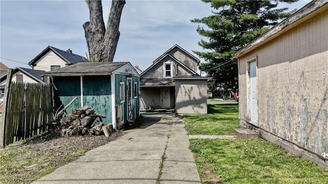 610 N 2nd St, Dennison, OH 44621 - view of front of house featuring fence, a storage unit, an outbuilding, and a front lawn
